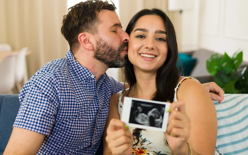 A happy couple holds up a sonogram