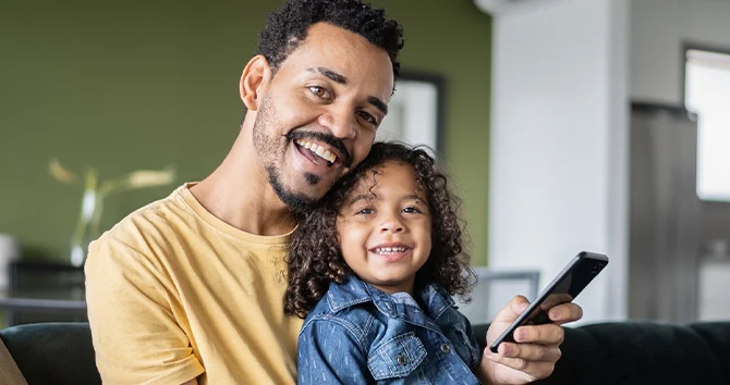 a smiling person with a child holding a phone